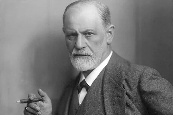 Imagem em preto e branco revela Freud usando paletó e segurando um charuto com a mão esquerda.